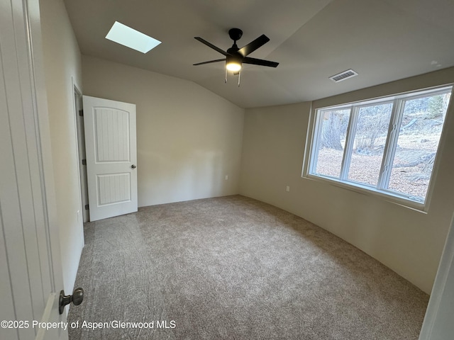 carpeted empty room with lofted ceiling with skylight and ceiling fan