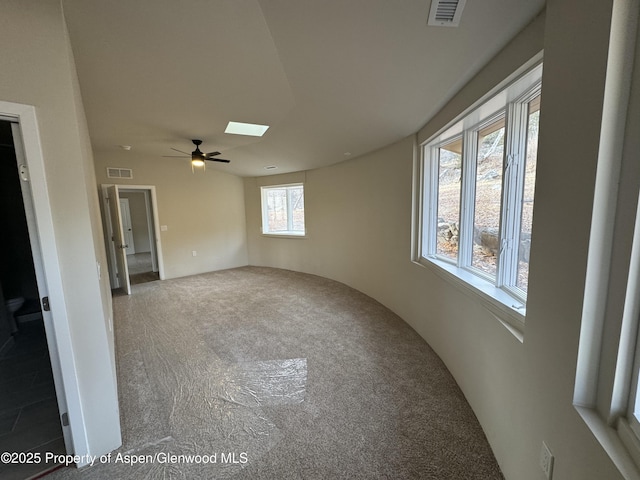 carpeted empty room with a skylight and ceiling fan