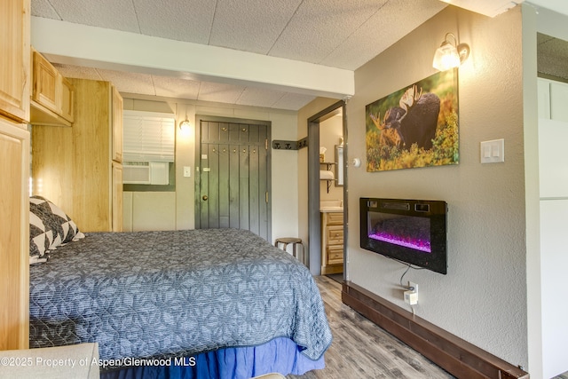 11101 County Road 117 Unit E-5, Glenwood Springs, CO 81601 - bedroom with wood finished floors, a glass covered fireplace, connected bathroom, and cooling unit
