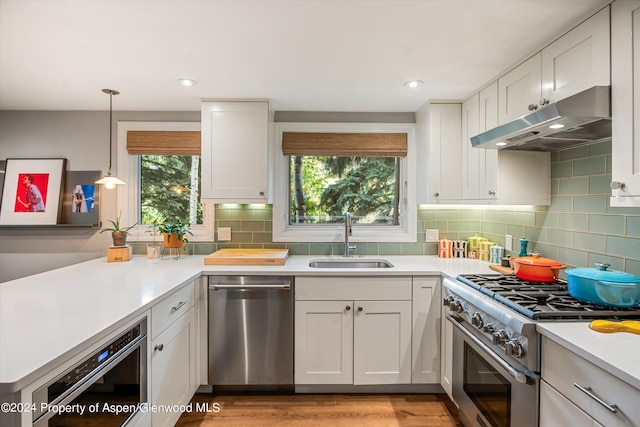 kitchen with white cabinets, decorative light fixtures, stainless steel appliances, and sink