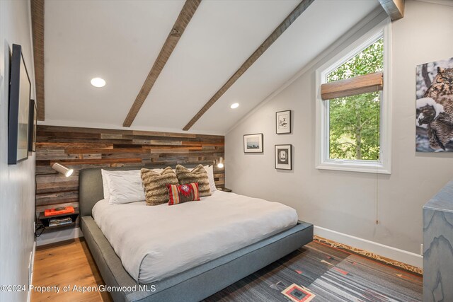 bedroom featuring hardwood / wood-style floors, lofted ceiling, and wooden walls