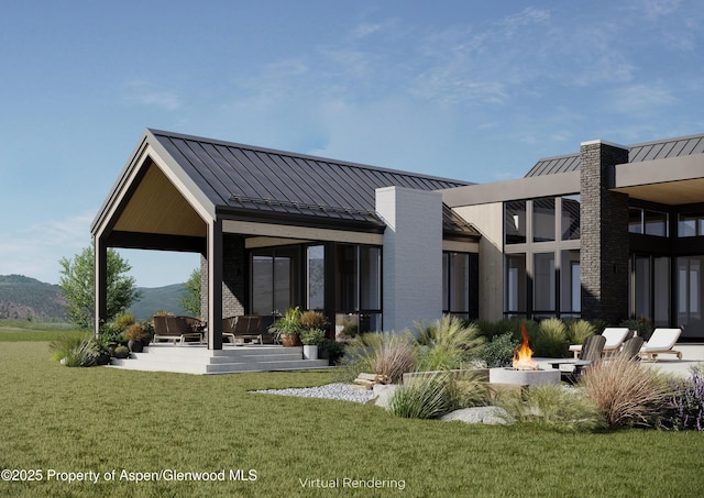 rear view of property featuring a mountain view, a yard, and an outdoor fire pit