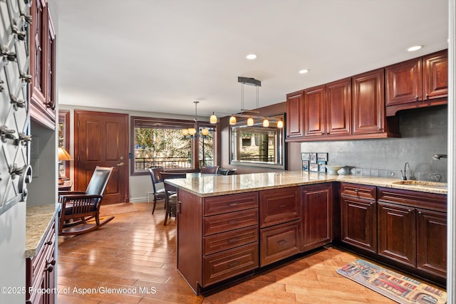 kitchen with a sink, recessed lighting, a peninsula, and light stone counters