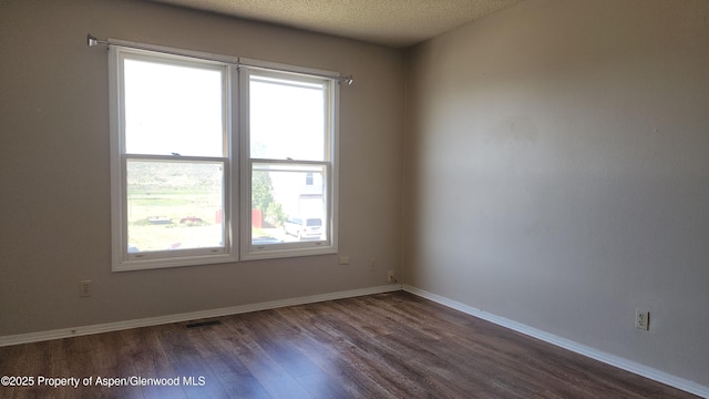 3863 W 6th St, Craig, CO 81625 - empty room featuring dark wood-type flooring, healthy amount of natural light, baseboards, and a textured ceiling