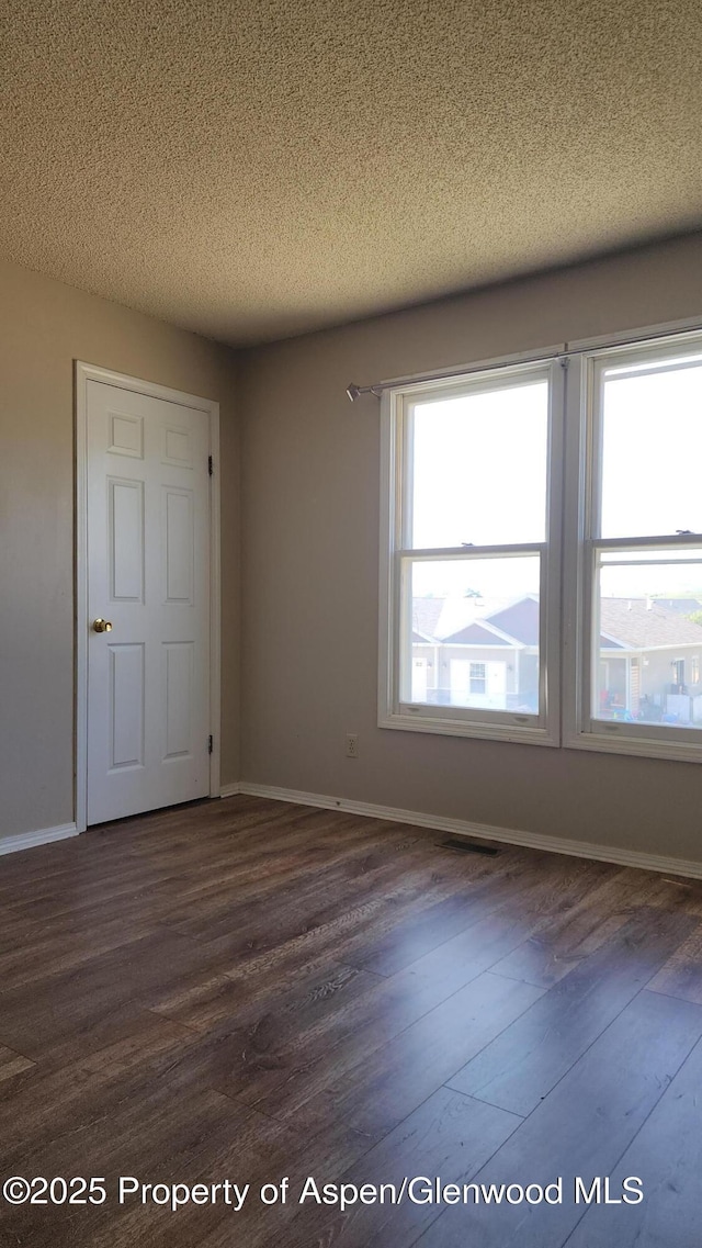 3863 W 6th St, Craig, CO 81625 - unfurnished bedroom featuring dark wood-style flooring, a textured ceiling, and baseboards