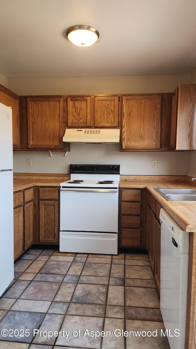 3863 W 6th St, Craig, CO 81625 - kitchen with white appliances, under cabinet range hood, light countertops, brown cabinets, and a sink