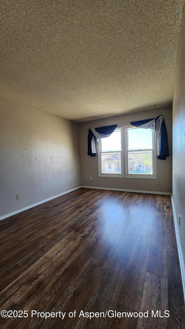 3863 W 6th St, Craig, CO 81625 - unfurnished room featuring a textured ceiling, dark wood-type flooring, and baseboards