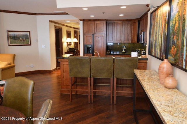 kitchen featuring crown molding, dark hardwood / wood-style flooring, paneled fridge, and light stone counters