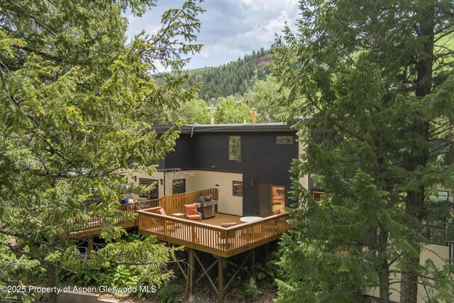 1501 Maroon Creek Rd # 2, Aspen, CO 81611 - rear view of property with a forest view, a wooden deck, and stucco siding