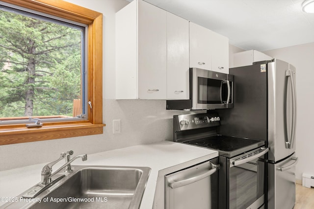 1501 Maroon Creek Rd # 2, Aspen, CO 81611 - kitchen featuring appliances with stainless steel finishes, white cabinetry, light countertops, a baseboard radiator, and light wood-style floors