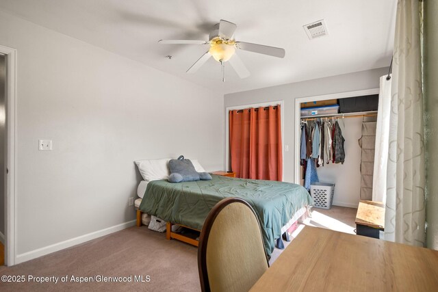 carpeted bedroom featuring two closets, baseboards, a ceiling fan, and visible vents