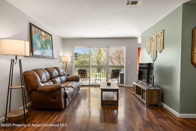 living room featuring visible vents, baseboards, and wood finished floors