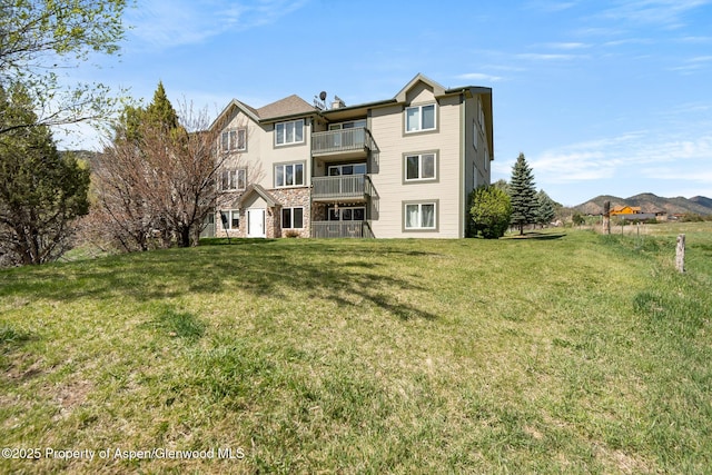 rear view of house with a lawn and a balcony