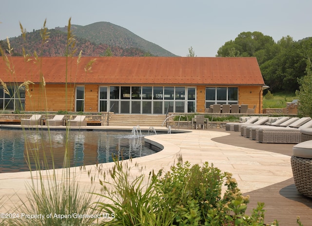 view of pool featuring outdoor lounge area, a mountain view, pool water feature, and a patio