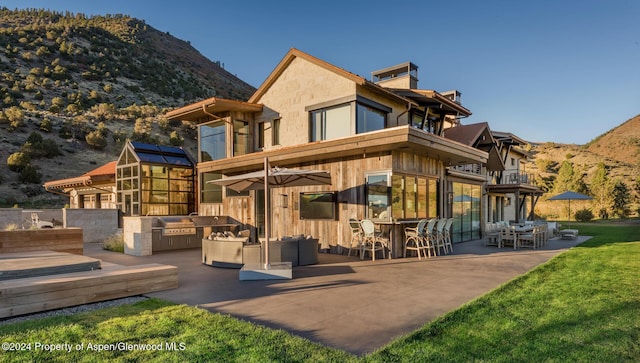 back of house with a mountain view, a balcony, and exterior kitchen