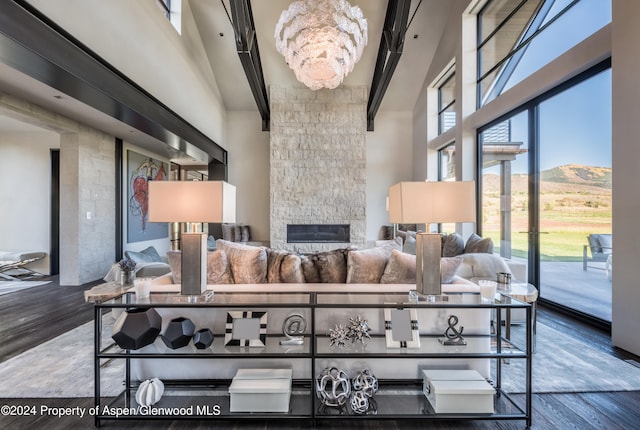 living room featuring a mountain view, hardwood / wood-style floors, a stone fireplace, and a notable chandelier