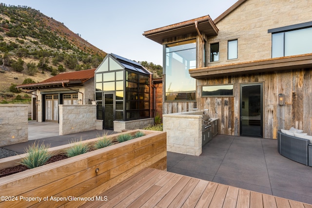 wooden terrace featuring a mountain view, a patio, and exterior kitchen