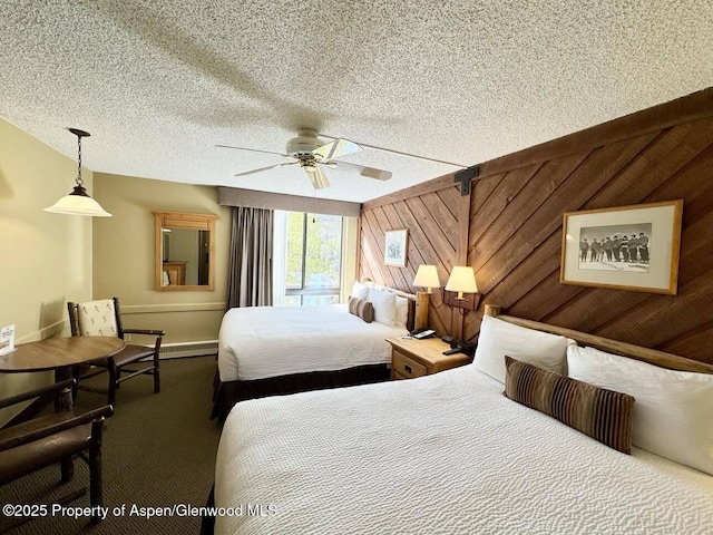 300 Carriage Way Unit 614, Snowmass Village, CO 81615 - carpeted bedroom with baseboards, a textured ceiling, wooden walls, a baseboard radiator, and ceiling fan