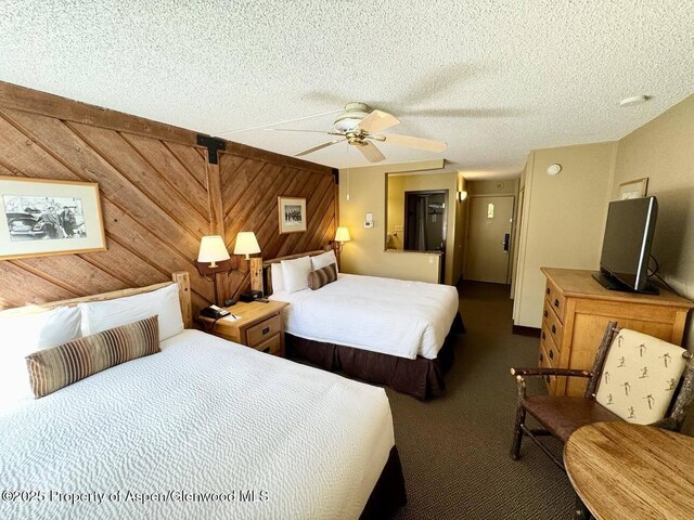 300 Carriage Way Unit 614, Snowmass Village, CO 81615 - bedroom with wood walls, carpet, ceiling fan, and a textured ceiling