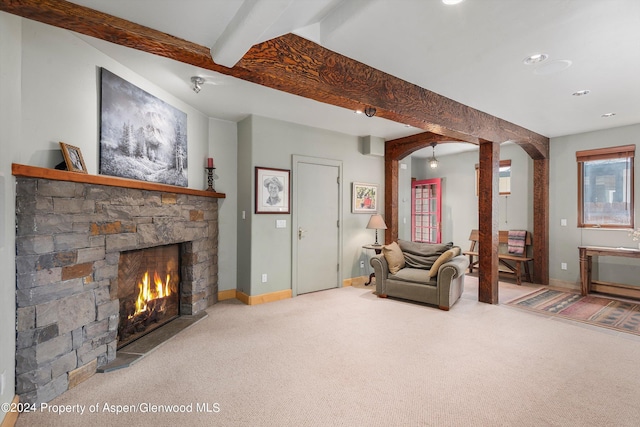 living area featuring arched walkways, carpet, beamed ceiling, a fireplace, and baseboards
