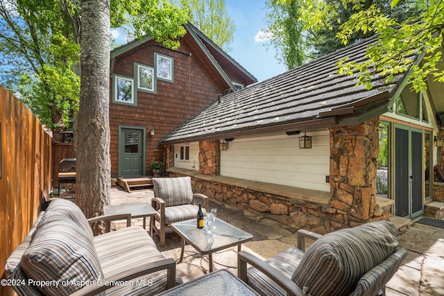 view of patio / terrace featuring fence, an outdoor hangout area, and a garage