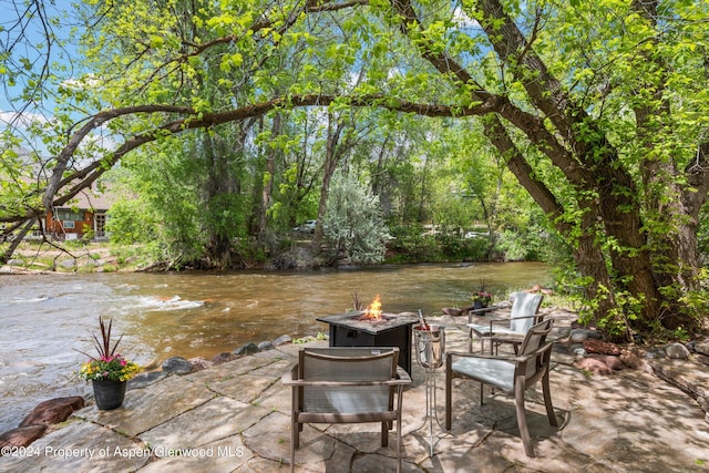 view of patio / terrace featuring an outdoor fire pit and a water view