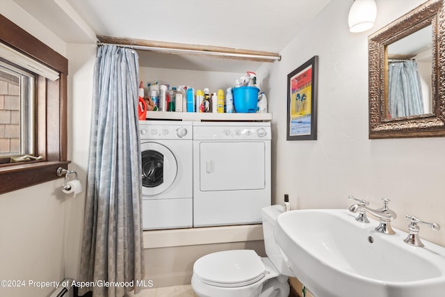 bathroom with a sink, washer and dryer, shower / tub combo, and toilet