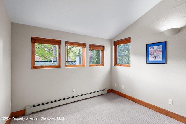 carpeted empty room featuring baseboard heating, vaulted ceiling, and baseboards