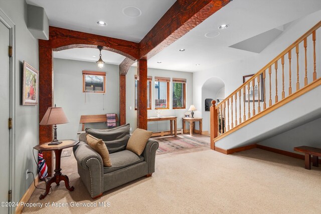 carpeted living area featuring arched walkways, beam ceiling, recessed lighting, baseboards, and stairway