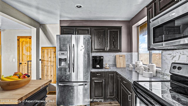 kitchen featuring dark cabinets, decorative backsplash, appliances with stainless steel finishes, and wood finished floors