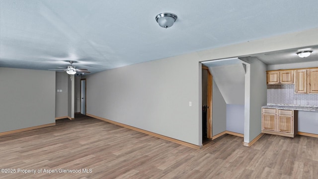 unfurnished living room featuring baseboards, a ceiling fan, and light wood finished floors