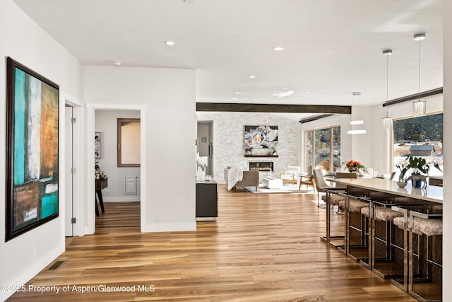 dining space with a large fireplace, visible vents, wood finished floors, and recessed lighting