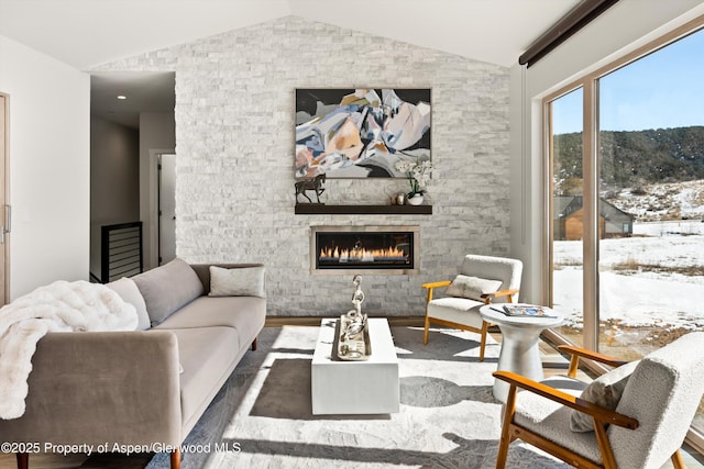 living area featuring vaulted ceiling, a fireplace, and wood finished floors