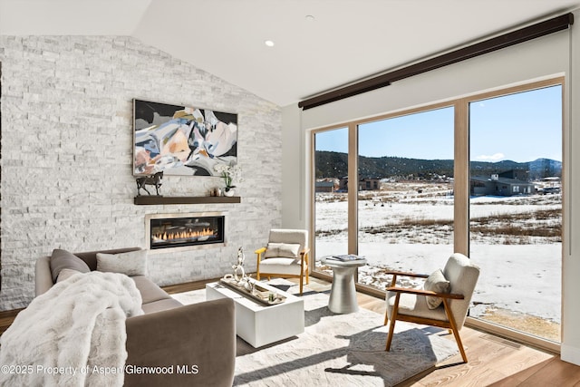 living room featuring a large fireplace, visible vents, vaulted ceiling, and wood finished floors