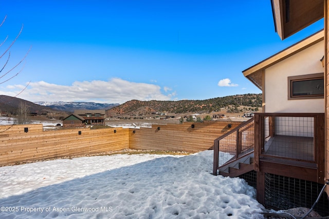 yard covered in snow with fence and a mountain view