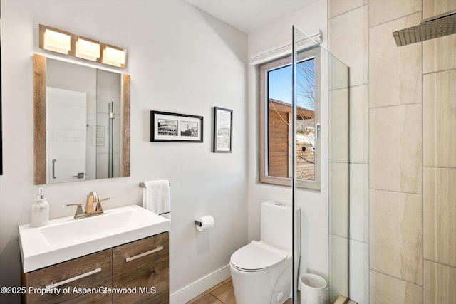 full bathroom featuring toilet, a stall shower, baseboards, and vanity