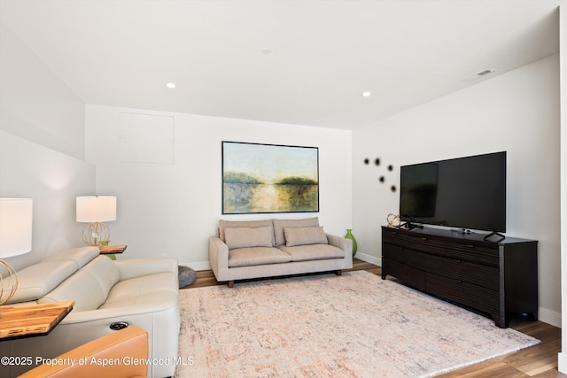 living room with recessed lighting, visible vents, baseboards, and wood finished floors