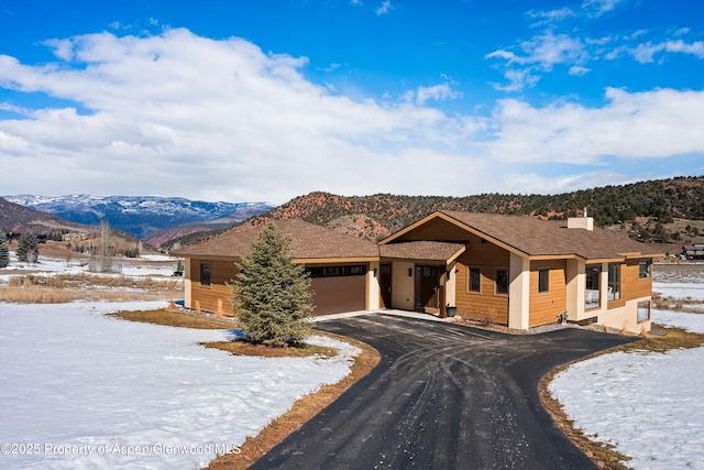 view of front of house featuring a garage, aphalt driveway, and a mountain view