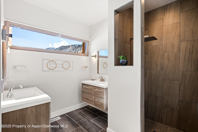 full bath featuring visible vents, tiled shower, vanity, and baseboards