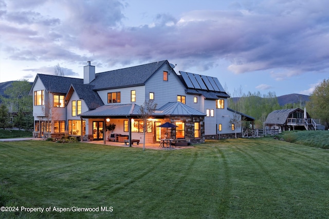 rear view of house with a lawn, a mountain view, and solar panels