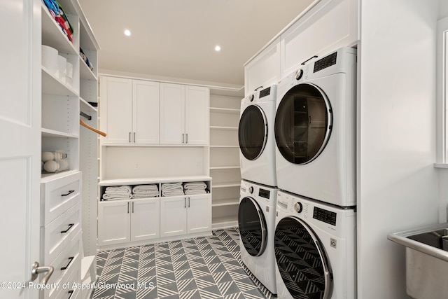 laundry area with cabinets, stacked washing maching and dryer, and sink