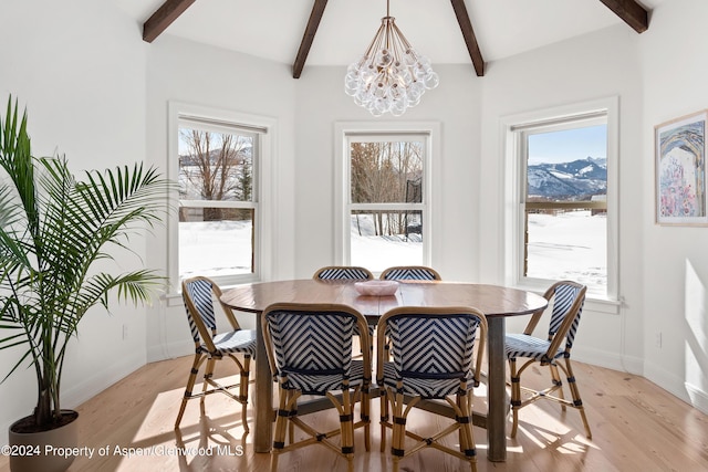 dining room with a mountain view, beam ceiling, light wood-type flooring, and a chandelier