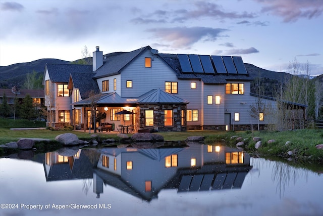 back house at dusk featuring a mountain view, a patio area, and solar panels