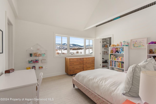 bedroom with a mountain view, light colored carpet, and lofted ceiling