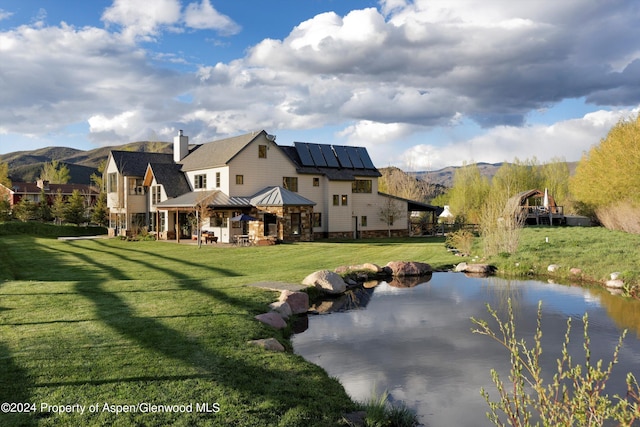 back of property featuring a mountain view, a gazebo, solar panels, and a lawn