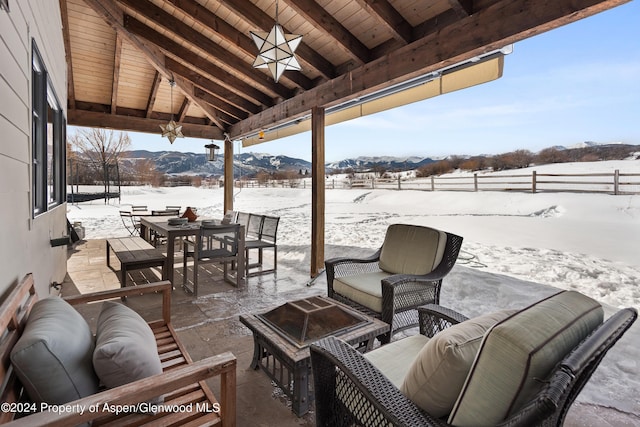 snow covered patio with a fire pit, a mountain view, and a gazebo