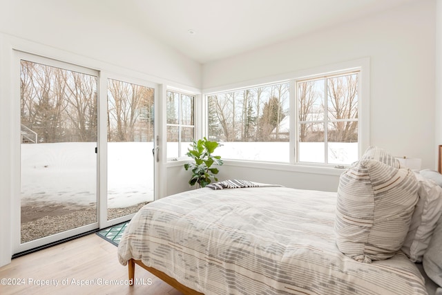 bedroom with light wood-type flooring, access to outside, and vaulted ceiling