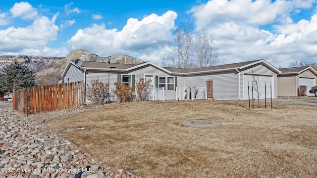 ranch-style house featuring a front yard, fence, and an attached garage