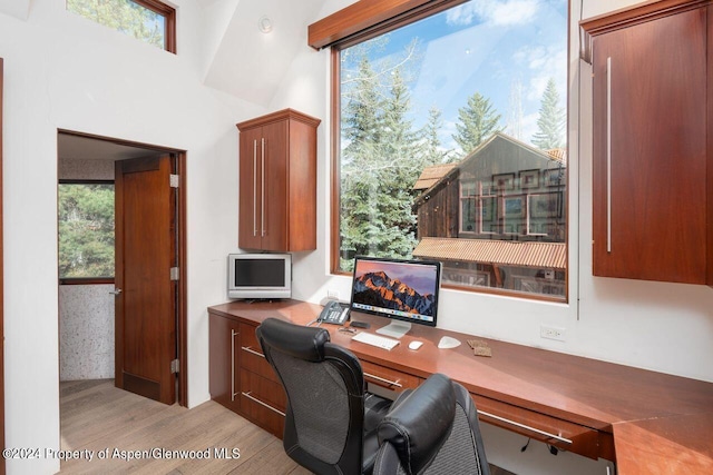 office space featuring a wealth of natural light, built in desk, and light wood-style floors