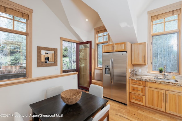 kitchen with a healthy amount of sunlight, light brown cabinets, lofted ceiling, a sink, and appliances with stainless steel finishes